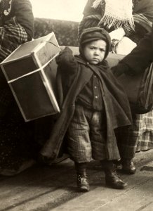 An immigrant boy carries luggage at Ellis Island. photo