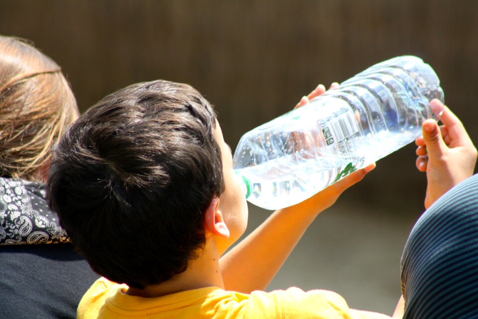 Child drinking water thirsty boy drinking brown bottle