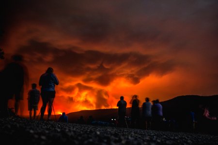 People watch and photograph the Sprague Fire from the beach at Fish Creek Picnic Area