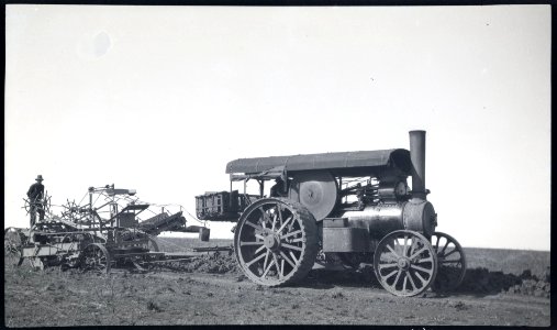 Steam tractor pulling elevating grader shifting dirt to road beside grader in flat country photo