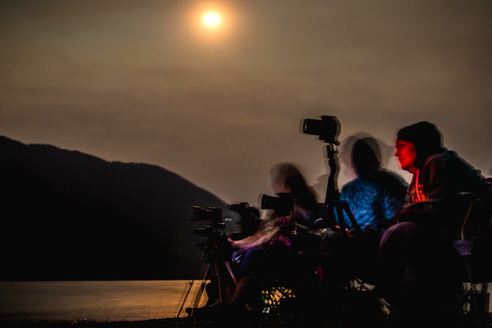 People watch and photograph the Sprague Fire from the beach at Fish Creek Picnic Area