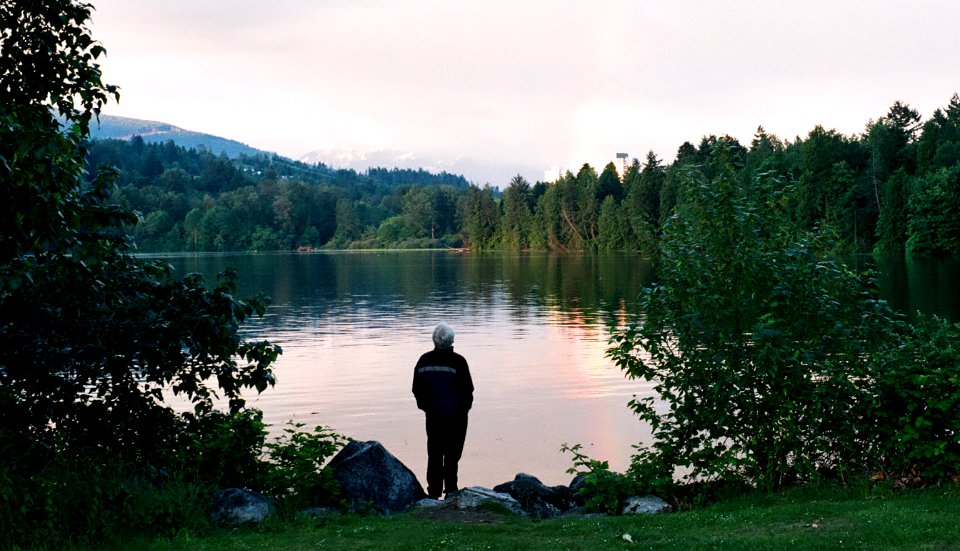 man looking at rainbow on lake photo