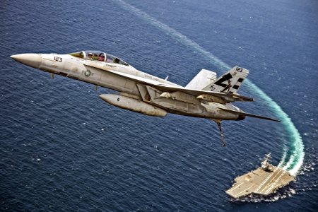 Boeing F/A-18F Super Hornet (BuNo 166969) of VX-23 (STRIKE TEST painted on fuselage) flies over the USS Gerald R. Ford