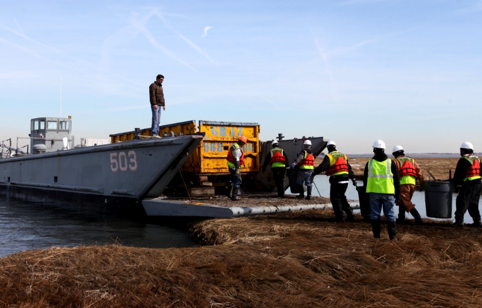 Ground crew transfers debris to watercraft for removal at Lido Beach WMA.