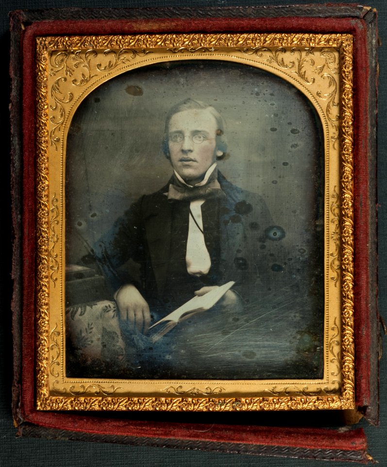 Daguerreotype of a bespectacled young man reading. 1850s