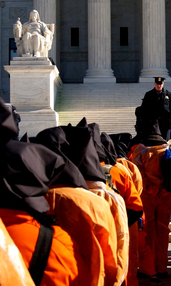 In Black Hoods & Orange Jumpsuits In Front Of "The Contemplation of Justice" Statue By James Earle Fraser At The International Day To Shut Down Guantanamo Bay, Supreme Court (Washington, DC)