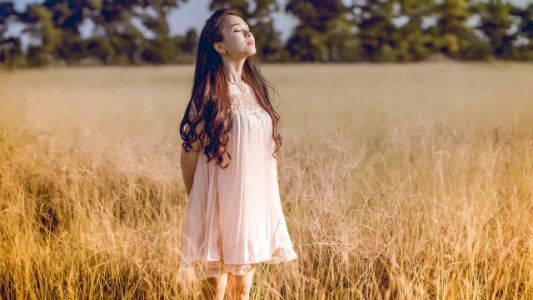 Vietnamese woman standing in the grass and closing eyes
