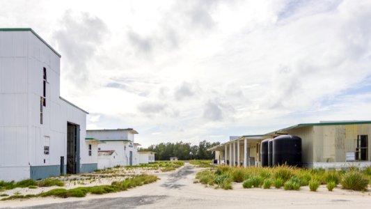 Looking west towards historic buildings on Midway Atoll: torpedo shop with parachute tower, machine shop, carpentry shop, storage buildings, and the transportation building