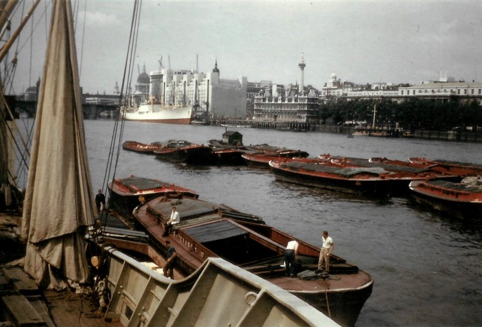 River Thames Cargo Barges , St Catherines Wharf, Monument to the Great Fire of London , London Bridge , Tower Bridge , St Pauls Cathedral photograph taken by Fred Burgin (opposite Tower of London)