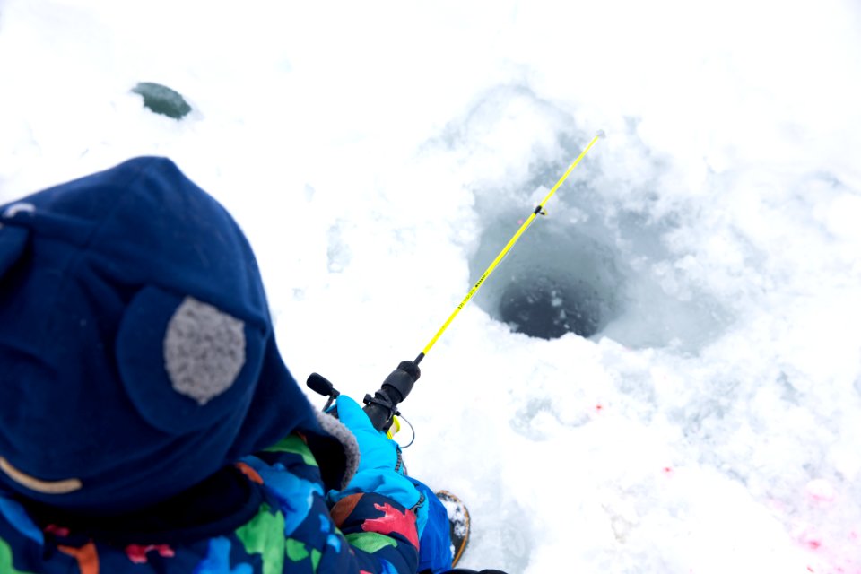 A small boy and family ice fishing.