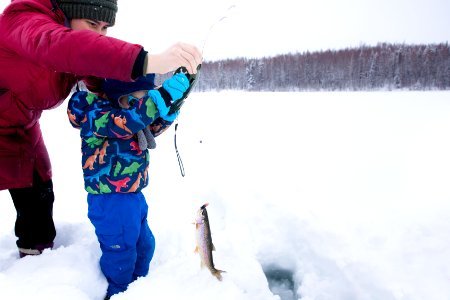 A small boy and family ice fishing.