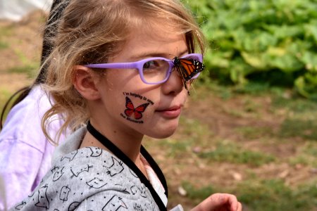 Monarch butterfly rests on student's glasses