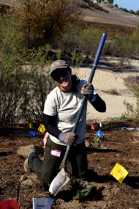 Partner holds shovel next to plant