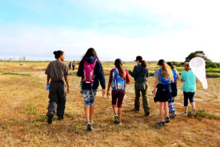 Service biologist Lara Drizd leads some of the young ladies of the FirstBloom on a beach walk providing an immersive learning experience allowing the girls to touch, smell, and listen to the nature that surrounds them.