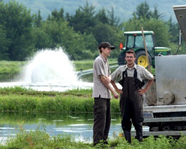 Hatchery workers discuss a rearing pond