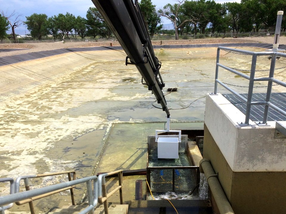 Crane water bucket lowered into pond kettle holding endangered fish at Horsethief Canyon Native Fish Facility, Fruita Colorado