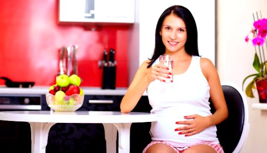 pregnant woman drinking water in kitchen photo