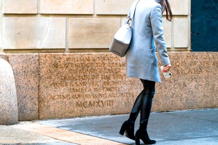 Leather and wool coat ensemble in neutral colors, woman walking with mobile phone