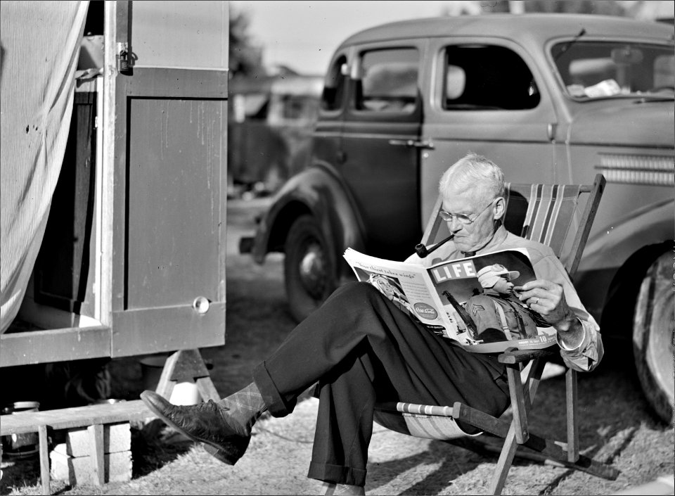 The Easy Life: Winter tourist reading a magazine beside his trailer home. Sarasota trailer park, Sarasota, Florida, January 1941.