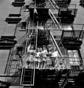 Gallery Seats: New York, New York. Italian-Americans watching parade on Mott Street and flag raising ceremony in honor of boys from the neighborhood in the United States Army, 1942.