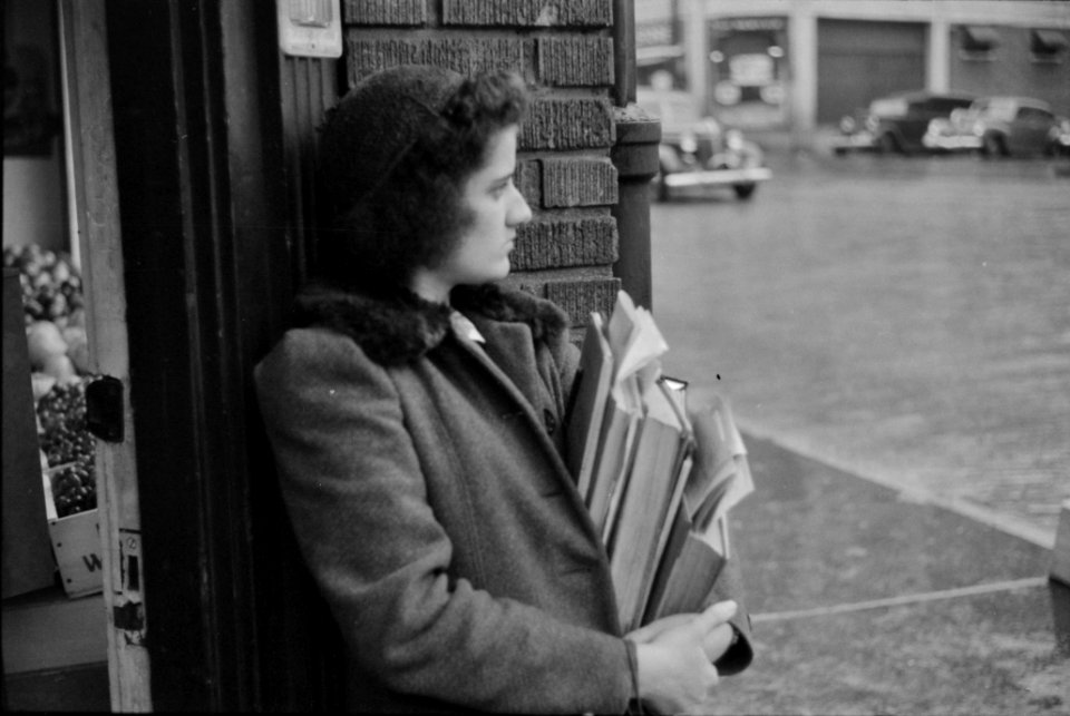 Young school girl waiting for a bus on a rainy day in Norwich, Connecticut. November 1940