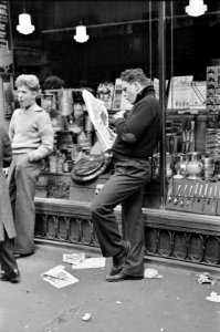 Street scene on 38th Street near 7th Avenue, New York City. Teenager reading newspaper, November 1936
