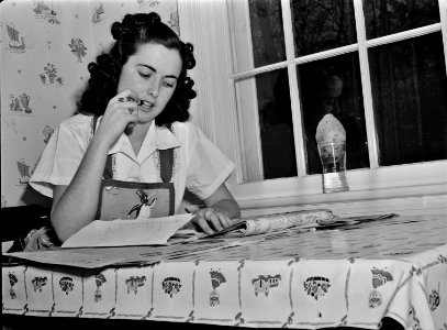 Check it Twice: A young woman deliberates over her shopping list, February 1942. This photo was taken as part of a series to inform the public on tips for the conservation of resources during wartime. Original caption below. photo