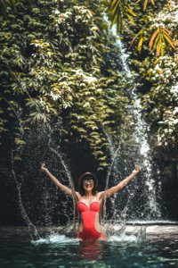 Happy Young woman tourist with straw hat in the deep jungle with waterfall. Real adventure concept. Bali island. photo