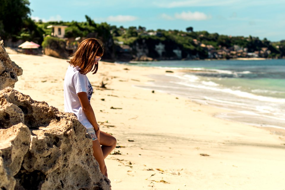 Beautiful young woman in sunglasses posing on the beach of a tropical island of Bali, Indonesia.