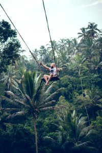 BALI, INDONESIA - DECEMBER 26, 2017: Man having fun on the swing with action camera in the jungle of Bali island, Indonesia. Rainforest, swing. photo