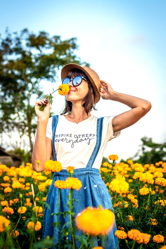 Close up portrait of happy and beautiful young woman relaxing enjoying the fresh beauty of gorgeous orange marigold flowers field in travel and holidays. Bali island.