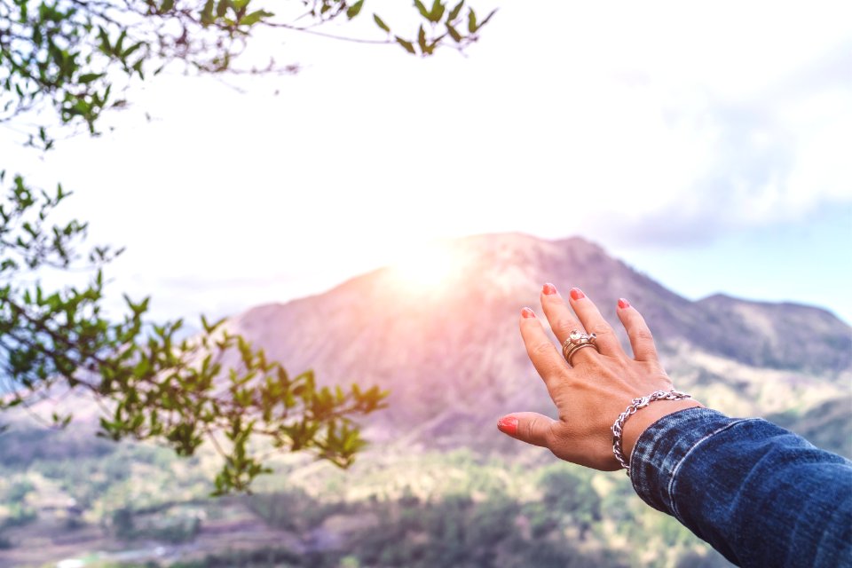 Woman hand on mountain background. Volcano Batur. Bali island.