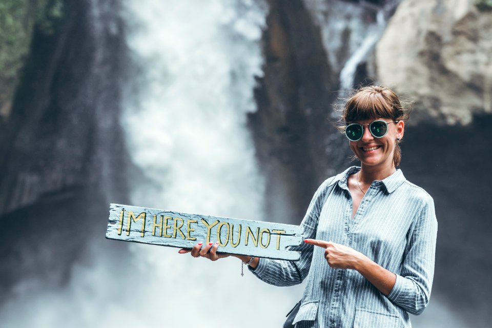Young woman posing close to waterfall on Bali island.