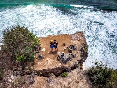 Aerial shot of couple on the cliff with ocean background. photo