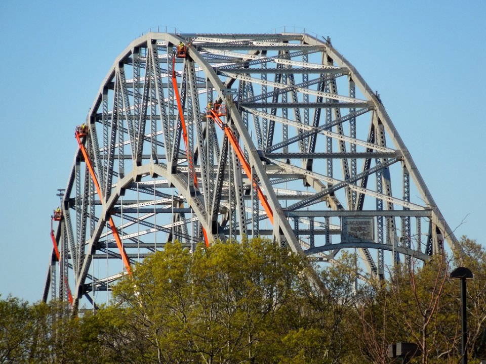 Four crews of steel workers on lifts above the Cape Cod Canal's Sagamore Bridge