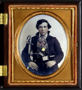 Unidentified soldier in Confederate uniform with cavalry sword and revolver.