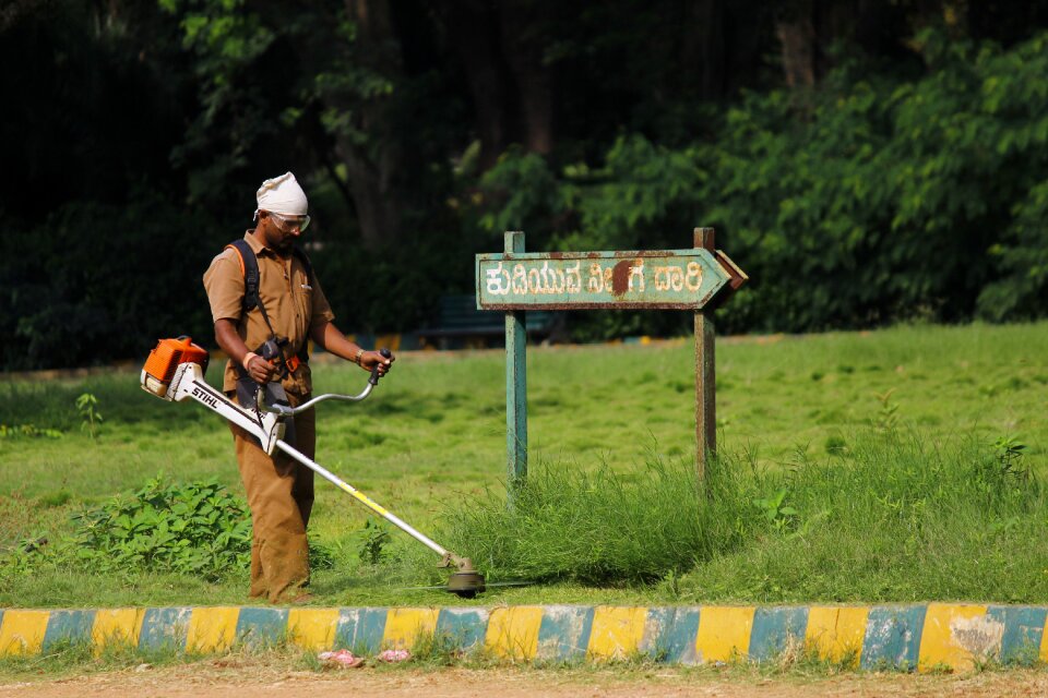 Indian worker garden maintenance grass cutter