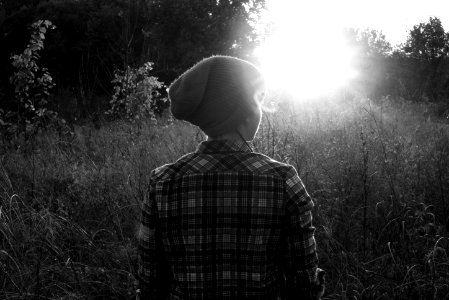 grayscale photo of person standing on grass field