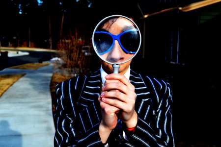 person using magnifying glass enlarging the appearance of his nose and sunglasses photo