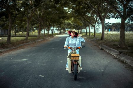 smiling woman riding scooter on road photo