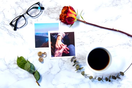 flat-lay photography of two photos, eyeglasses, and rose