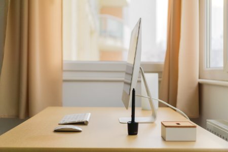 Apple iMac on wooden desk near window photo