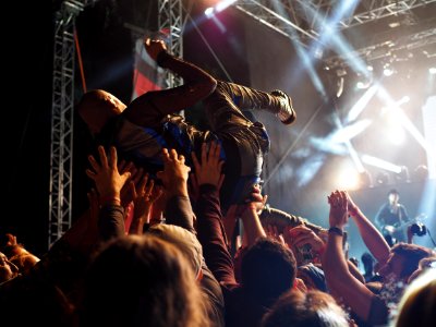 group of people carrying a person in front of the concert stage