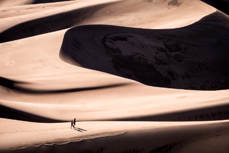two person walking on desert during daytime photo