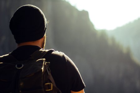 man wearing black t-shirt and knit cap fronting mountains photo