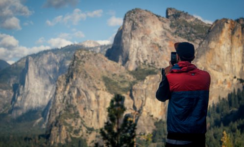 person taking photo of mountains during daytime photo