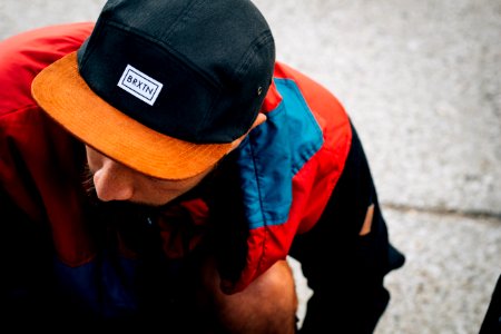 man wearing black and orange Baxin cap looking down photo