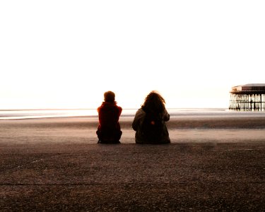 two people sitting and looking at the sea photo