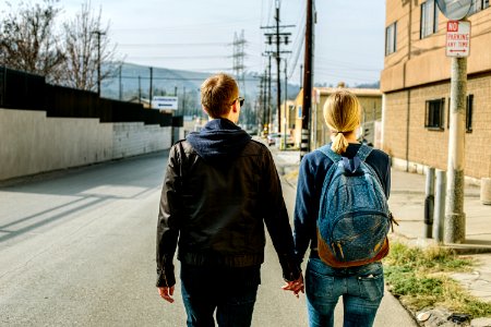 man holding hands of woman walks on concrete road photo