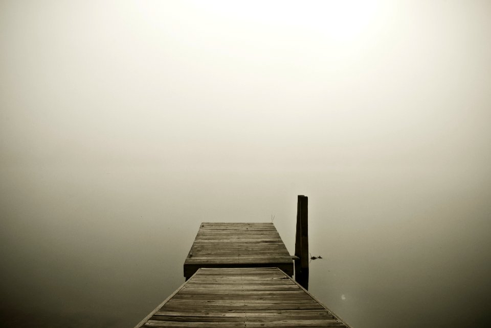 brown wooden pier on cloudy horizon